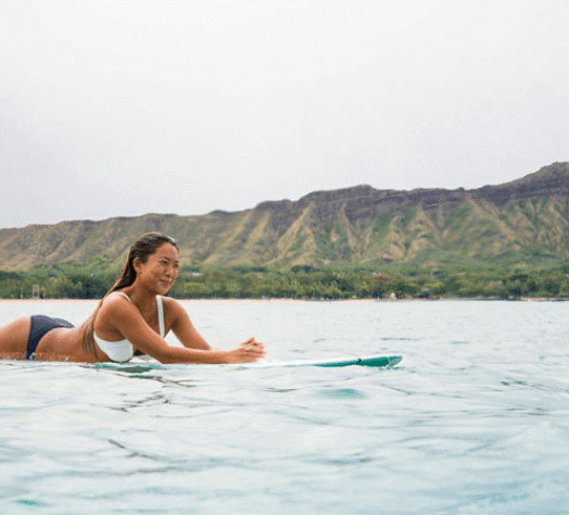 Surfer girl on a board in front of Diamondhead