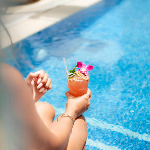 Holding a cocktail at the pool at halepuna