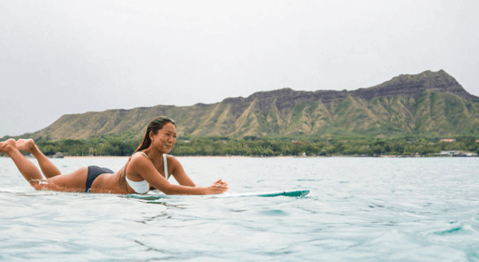 Woman on a longboard in front of Diamondhead